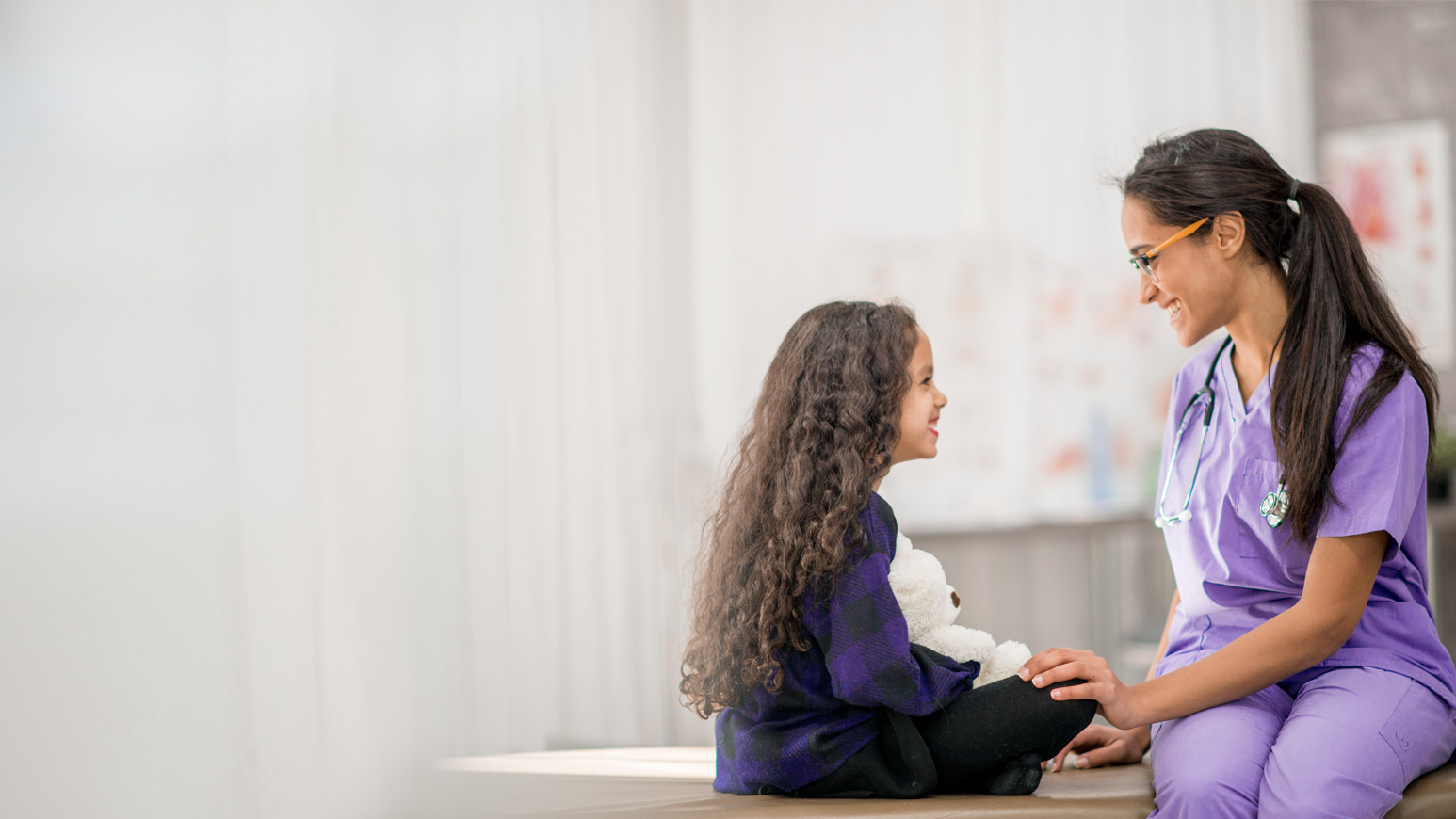 Veselības aprūpes speciālists slimnīcā sarunājas ar bērnu